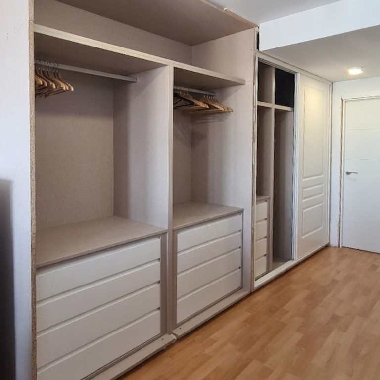 Interior de armario, combinando melamina blanca y lino textil cancún Armario moderno con estantes, cajones y barras para colgar ropa, en un entorno iluminado.